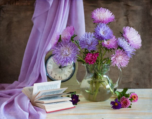 beautiful purple flowers and a vase of books on a wooden table. home decor. home interior.