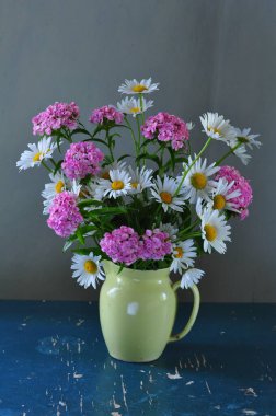 Mavi arka planda vazoda bir buket papatya. 