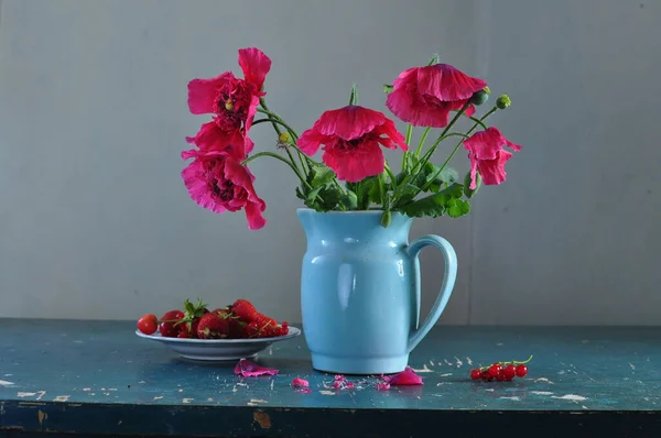 Hayat kırmızı petunya çiçekleri ve mavi kupalarla dolu 