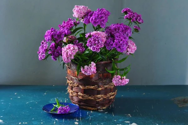 lilac flowers in the vase on the background of a concrete wall. a bouquet of lilac in a vase on a table.