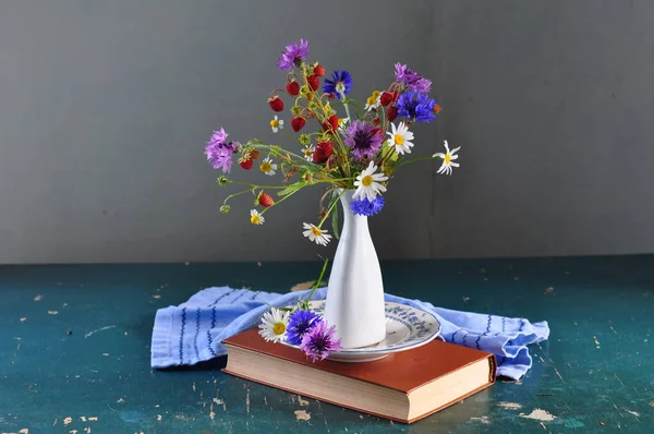 vase with flowers and a book