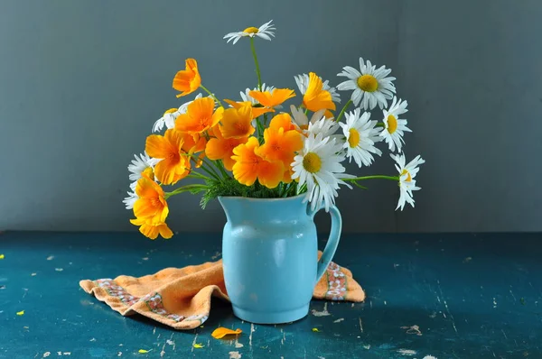 Güzel bir buket çiçek ve mavi arka planda bir vazo papatya. 