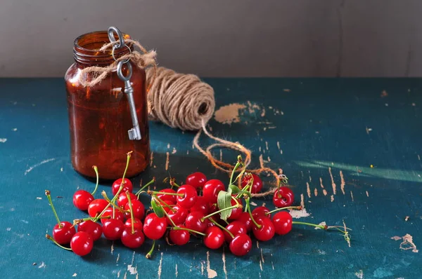 红樱桃和一瓶果汁放在木制桌子上 — 图库照片