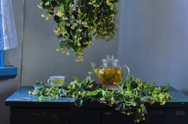 Bir fincan çiçekli çay ve ahşap bir masada çaydanlık. 