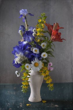 Masada mavi vazoda güzel yaz çiçekleri var.