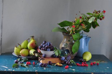 Mutfaktaki eski ahşap masada bir fincan taze meyveyle sakin bir hayat.