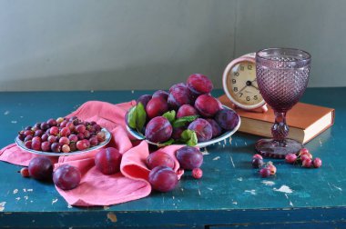 Durgun bir hayat. Bir fincan kırmızı çay, bir buket üzüm, erik ve elma. Sağlıklı beslenme kavramı.