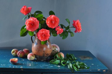 Vazoda kırmızı güller ve ahşap bir arka planda sürahi.