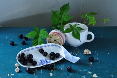 Bir fincan çay ve ahşap bir masada kuşüzümü.