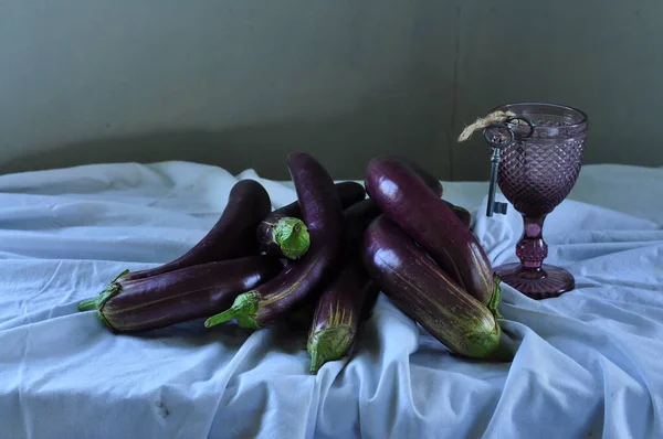 purple and red eggplant with a glass of water.
