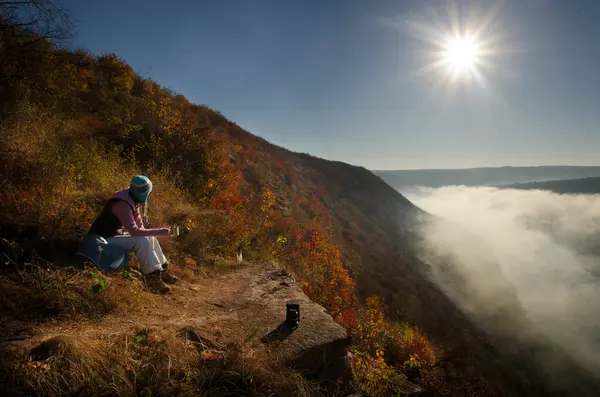 Sırt çantasıyla dağın tepesindeki dağlarda yürüyüş yapan genç bir kadın yürüyüşçü.