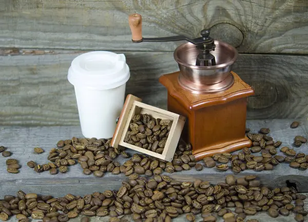 coffee mill, coffee beans and a coffee grinder. on the background of boards