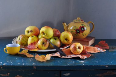 Bir fincan çay ve ahşap masada bir balkabağıyla durgun bir hayat.