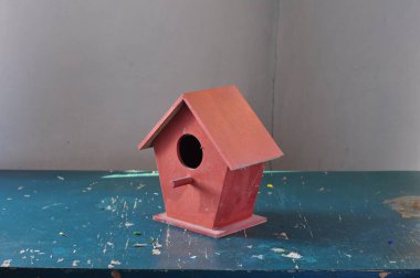 Beyaz arka planda kuş gözü olan kırmızı ahşap kuş evi..