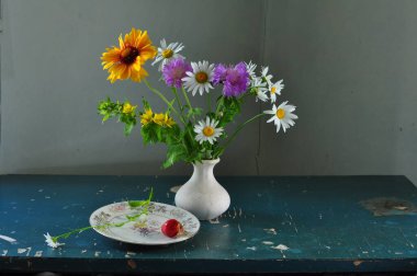 Masanın üzerinde bir buket çiçek ve vazo var.