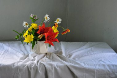 Vazodaki beyaz çiçeklerden oluşan güzel bir buket beyaz bir vazo ve gri bir arkaplan.