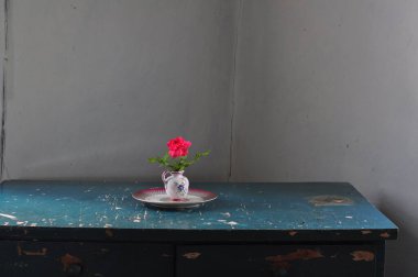 Tahta bir masadaki vazoda güzel bir çiçeğin yakın plan fotoğrafı.