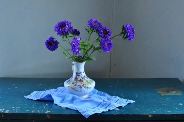 Bir buket çiçekle ve tahta bir masanın üzerinde çiçeklerle durgun bir hayat.