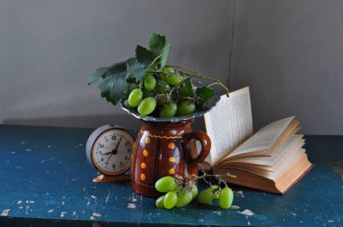 Bir buket üzüm, elma ve bir kitabın natürmortu.