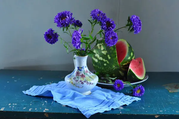 Bir sürahi sürahi ve bir sürahi çiçekle dolu bir buket ve mavi arka planda bir sürahi.