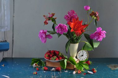 Bir buket kırmızı çiçek ve tahta bir masada bir bardak sütle durgun bir hayat.