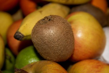 Arka planda muz ve elmalar olan meyve sepetinde yakın plan kivi.