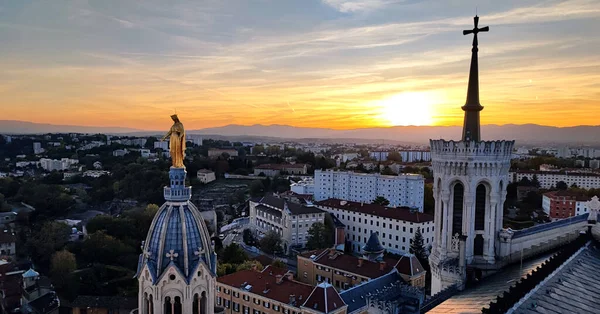 Kule ve gün batımında Fransa 'nın Lyon kentindeki Fourviere Katedrali' nin tepesindeki Bakire Meryem 'in ünlü altın heykeli.