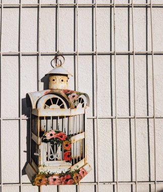 Beyaz arkaplanı olmayan, boyalı çiçekli paslı bir kafes.