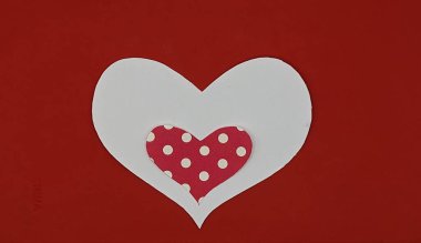 Kırmızı arka planda beyaz bir kalbin içindeki kağıt kırmızı ve beyaz noktalar.