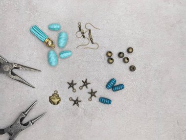 Zanaatkar kuyumcu masası, cımbız, boncuk, tılsım ve çimento arka planda kancalar, gölgeler