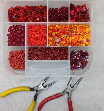 Kırmızı, sarı ve turuncu boncuklu mücevher kutusu, mücevher cımbızı.