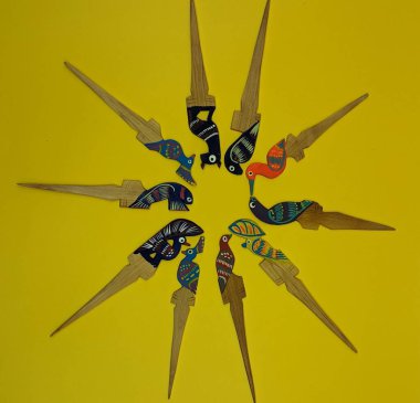 Meksika geleneksel el yapımı ahşap figürler sarı arka planda yuvarlak pozisyonda. Renkli kuşlar, balıklar ve jaguarlar