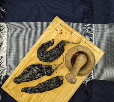 Meksika kuru biberleri, ahşap havan ve taban ve geleneksel mavi masa örtüsü. Çapraz