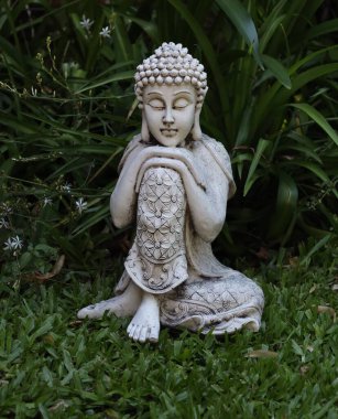 Siddharta Gautama Buda bahçesinde küçük beyaz çiçeklerle, ortada