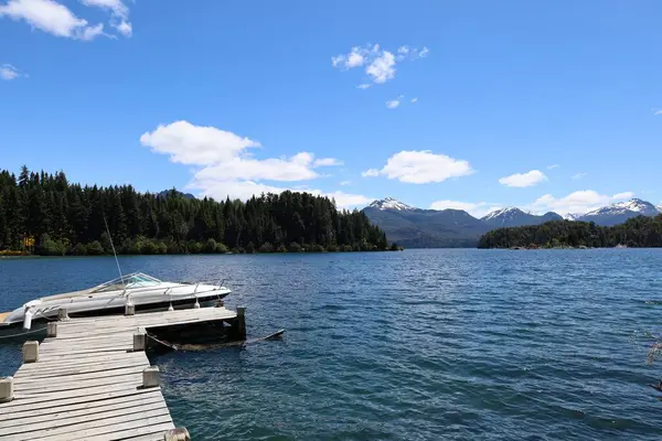 Ahşap iskele ve patagonya manzarasında beyaz tekne.