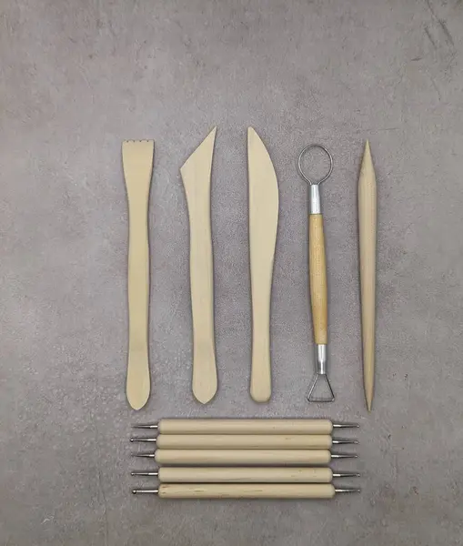 Combined wooden and metal sculpt tools on gray cement background