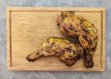 İki ızgara tavuk budu ahşap tabakta çimento arka planda