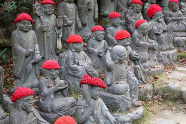 Kırmızı yün boncuklardaki Buda taş heykelleri