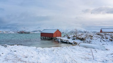 Kuzey Atlantik kıyısındaki güzel, renkli evler. Hillesoy ve Sommaroy adalarındaki ahşap yazlıklar. Göl kenarındaki kırmızı ev. Troms, Kuzey Norveç 'te tatiller. Kvaloya sahilinde kış, okyanustan gelen fırtınalı dalgalarla