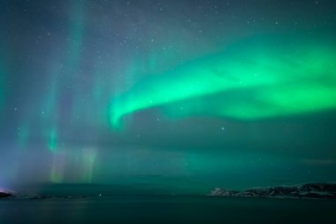 wonderful northern lights in Troms in the Lyngenalps. inspiring play of light in the night sky, aurora borealis near Tromso in Sommaroy, Norway clipart