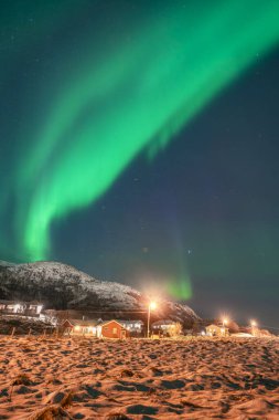 Hillesy köyünün üzerinde harika kuzey ışıkları. Parlak ışıklı evler ve sokak lambaları, yeşil Aurora Borealis 'li karanlık gökyüzünün tam zıttıdır. Kuzey Norveç 'te kış havası