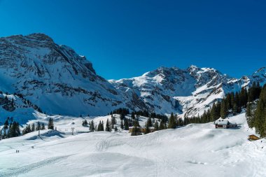 Spoor, tracor, track, line or ways in the Snow, Bregenzerwald 'da kış manzarası, dik kar örtülü dağlar, kayalar ve ağaçlar, Arlberg' de kar ve buz. Karlı dağlarda güneşli bir gün