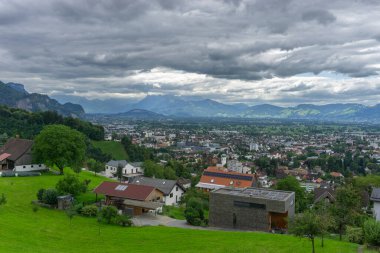 Dornbirn ve Rhein Vadisi 'ni gören, arka planda İsviçre' den dağları olan, çayırda park bankı olan bir panorama. Koyu bulutlar ve yeşil çimlerle dolu öğleden sonra. dinlenme yeri