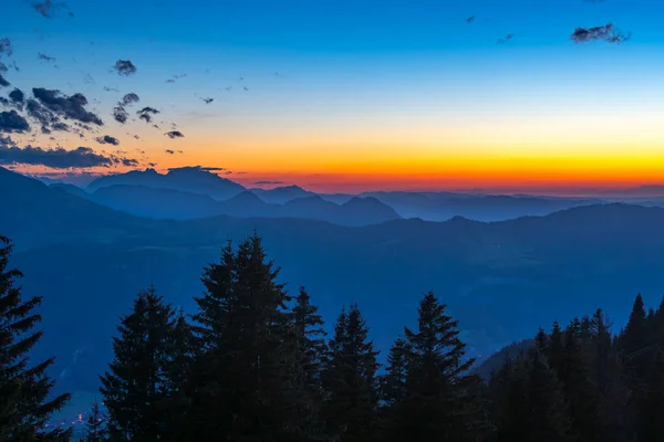 Mountain silhouettes in the panorama of the Bregenzerwald, with Sntis in the background. Sunset red and haze make the contours visible.