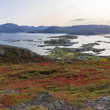 Nordkollen Dağı 'ndan Sommary ve Kvalya' ya kadar harika panoramik manzara, arka planda köy ve liman tesisleri ve rüzgar türbinleri ve Norveç 'te büyük sonbahar kırmızı renkli bitkiler, yürüyüş alanı