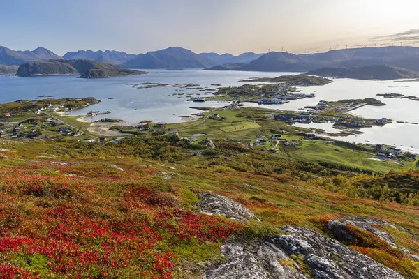 stock image wonderful panoramic view from Nordkollen mountain down to Sommary and Kvalya, with the village and the harbor facilities and wind turbines in the background and great autumnal red-colored plants, hiking area in Norway