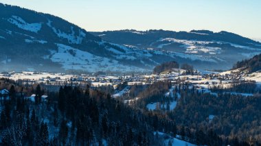 Alp köyü, kışın Avusturya 'da, vadide, dağların etrafındaki dağlarla birlikte merkezi kilise olan karlı bir yerleşim yeri, güzel bir çiftlik evi koleksiyonu, güzel kış manzarası.