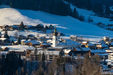 alpine village, Austria in winter, snowy scattered settlement with church as centre point in the valley, with mountains around, in the valley is a collection of farmhouses, beautiful winter landscape clipart