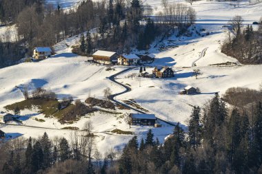 Alp köyü, kışın Avusturya, vadide dağlarla kaplı karlı bir yerleşim yeri, vadide, çayırlarla ormanlar arasında bir çiftlik evi koleksiyonu, güzel kış manzarası.