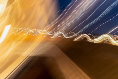 Renkli yüzeylerdeki dalgalı sarı ve beyaz ışık izleri, düzensiz yapılar ilginç bir resim gösteriyor